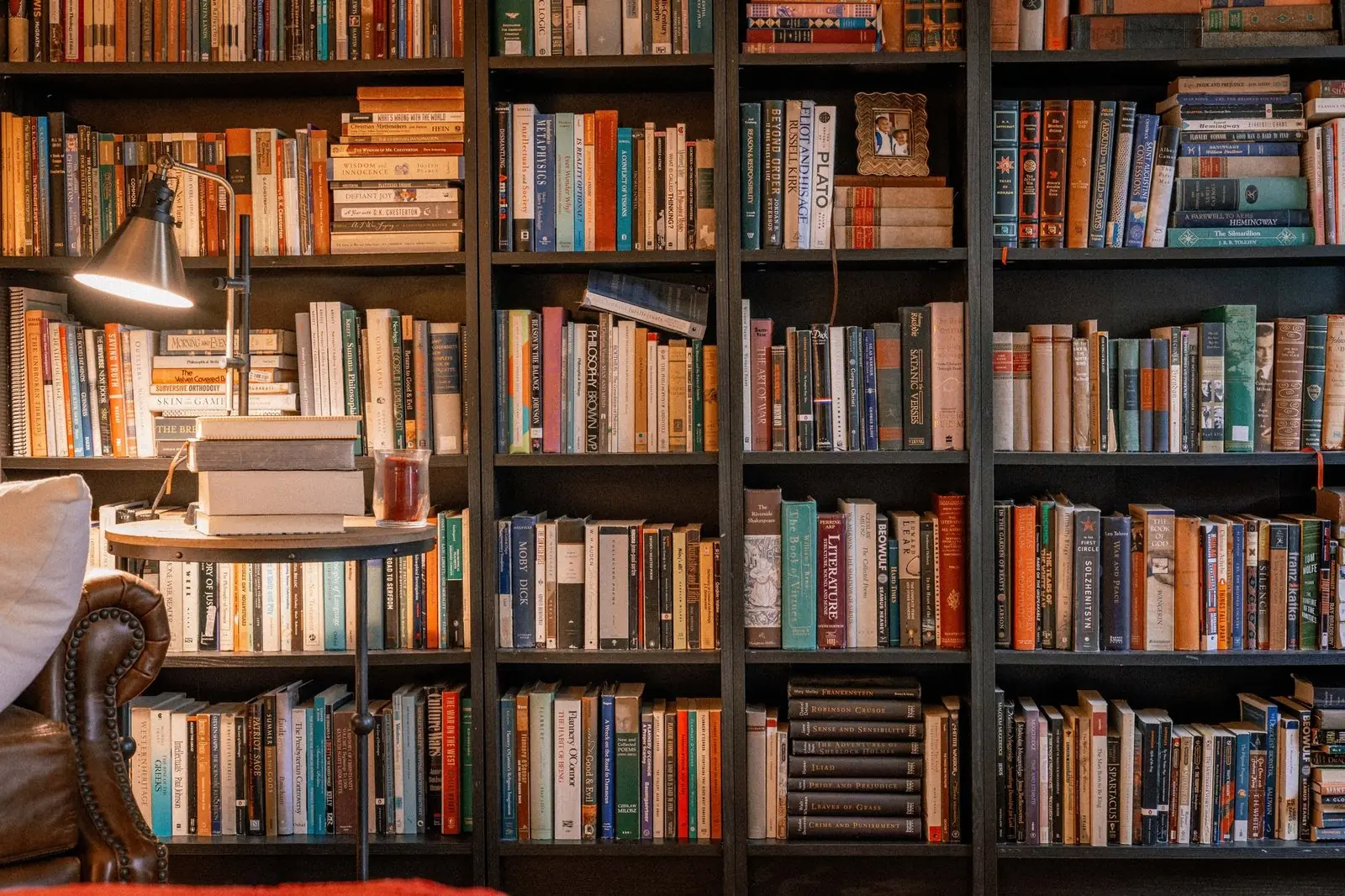Study with floor to ceiling bookshelves and a reading lamp