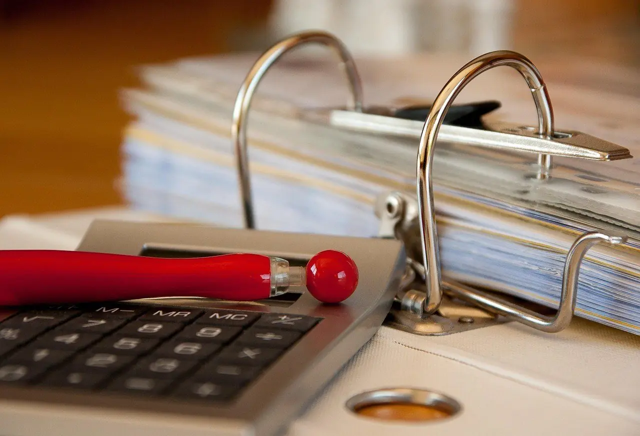 Ring binder of papers beside a calculator