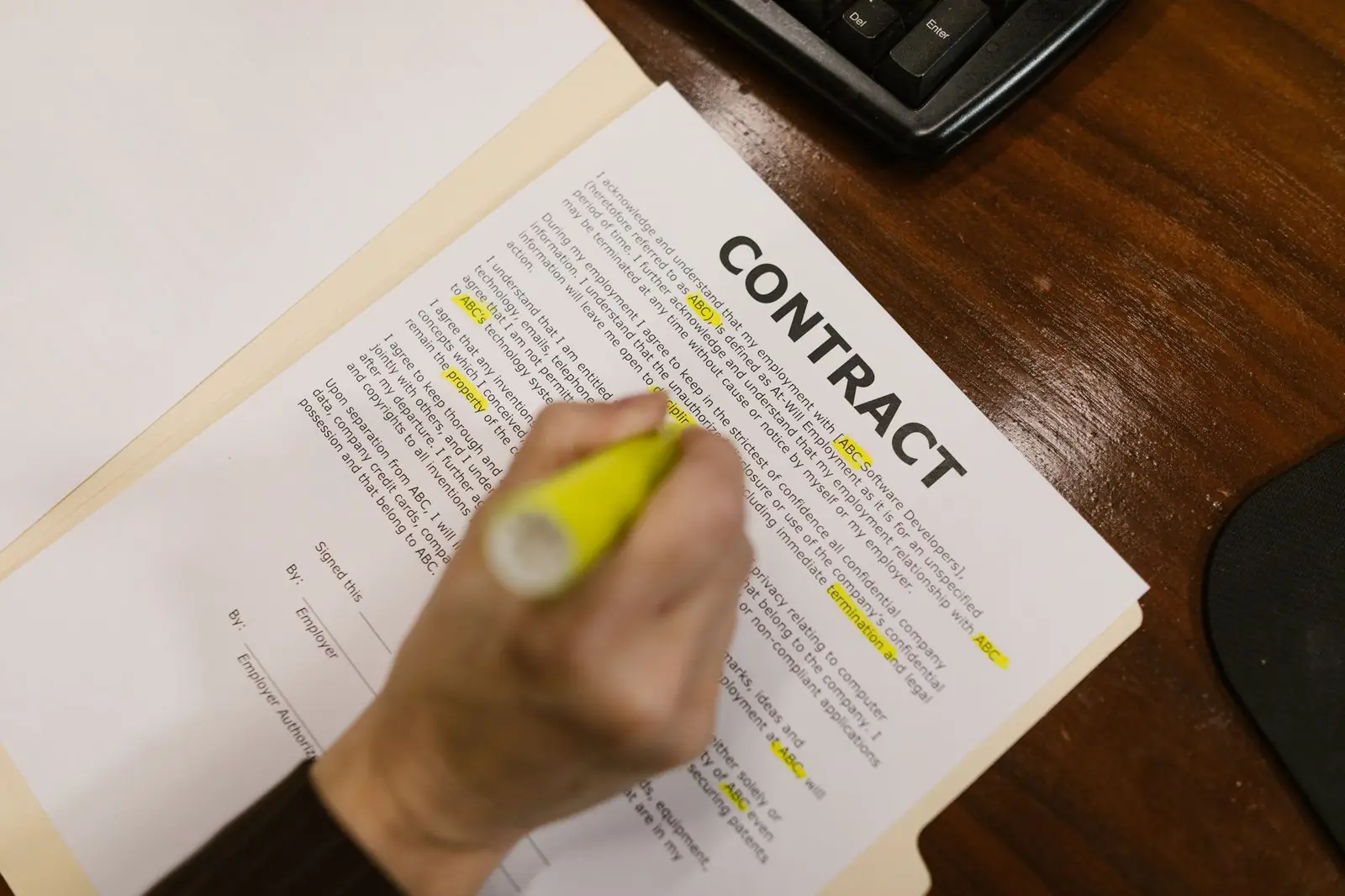 Hand highlighting clauses on a printed contract