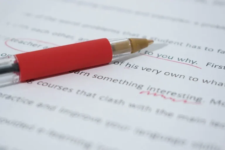 Red pen resting on a printed page with corrections