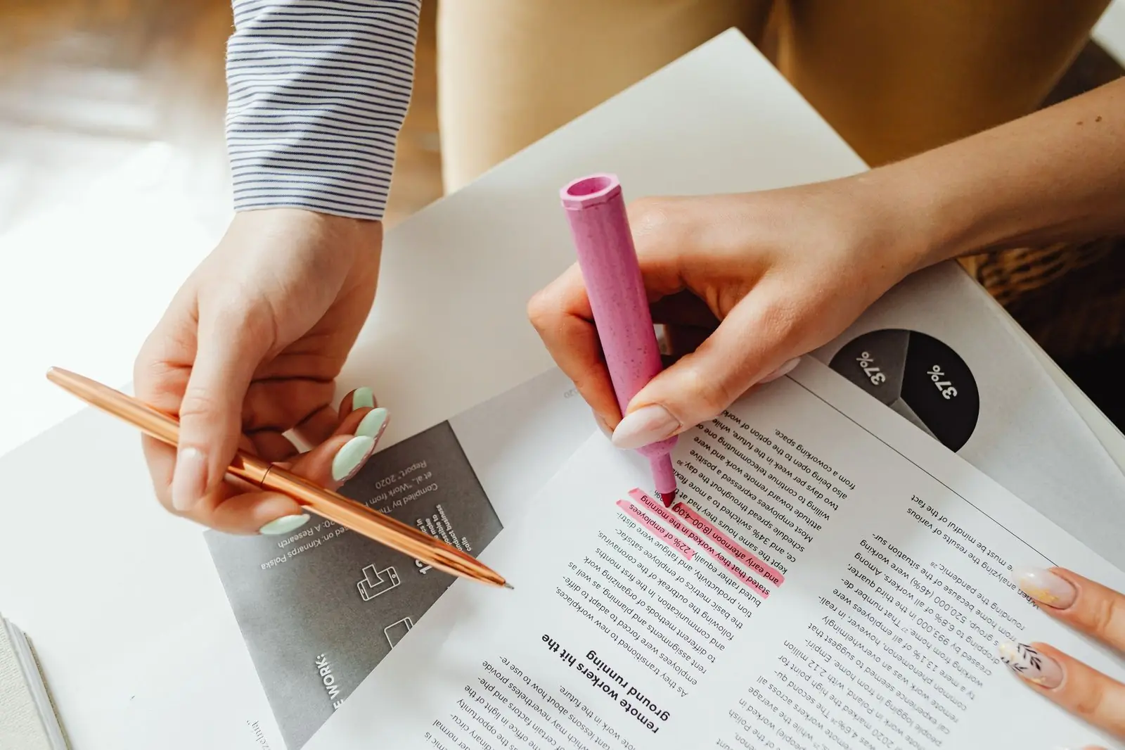 Two people highlighting lines in a printed document