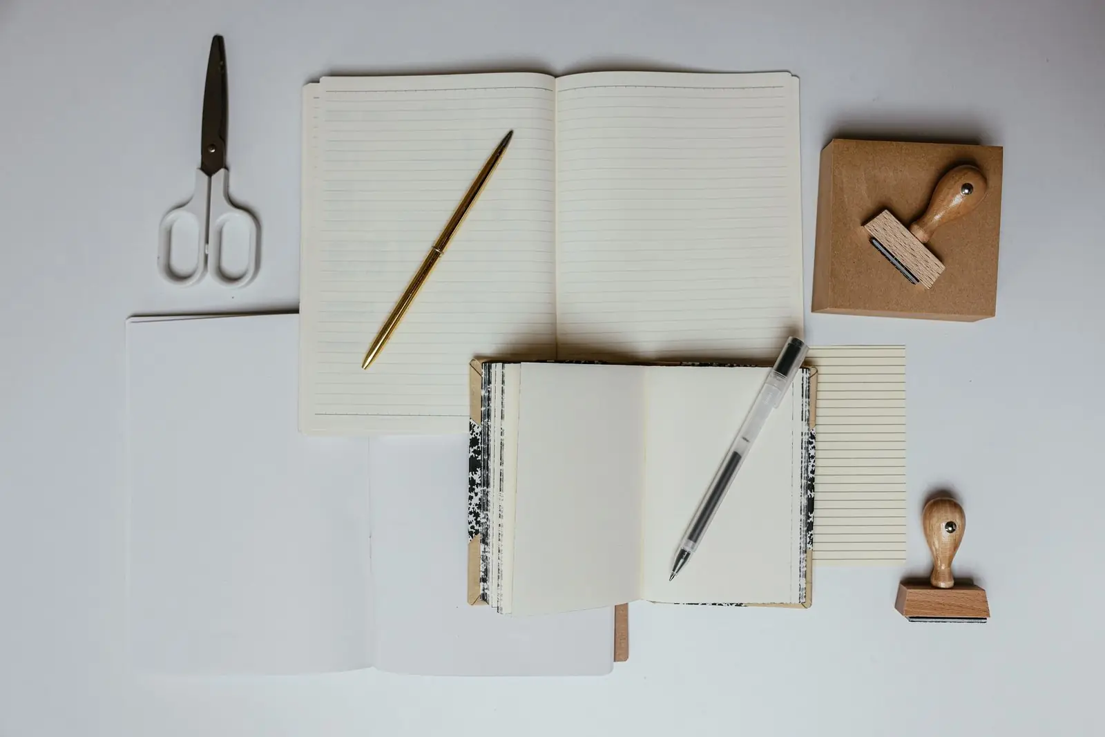 Notebooks, pen and a small stamp laid out on a desk