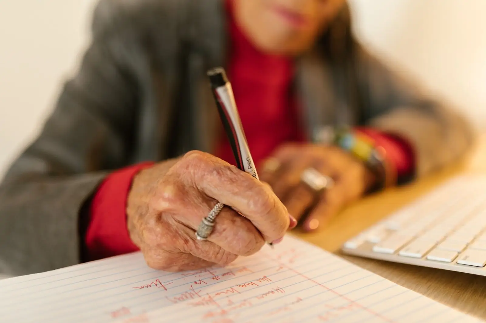 Older woman writing by hand at a desk