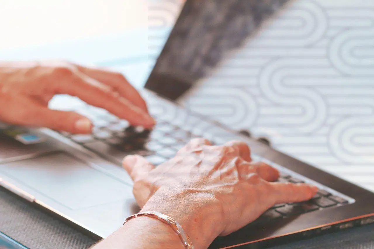 Older hands typing on a laptop